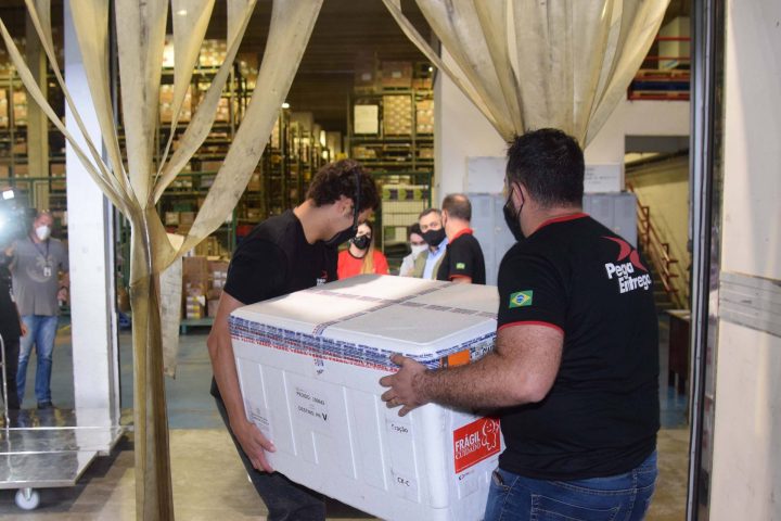 Funcionários descarregam doses de vacina que chegaram ao Paraná