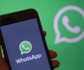 pessoa segurando celular que mostra o logo do whatsapp na tela