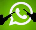 duas pessoas utilizando celular, logo do whatsapp aparece ao fundo