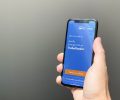 pessoa segurando celular com aplicativo para sacar o auxÃ­lio aberto