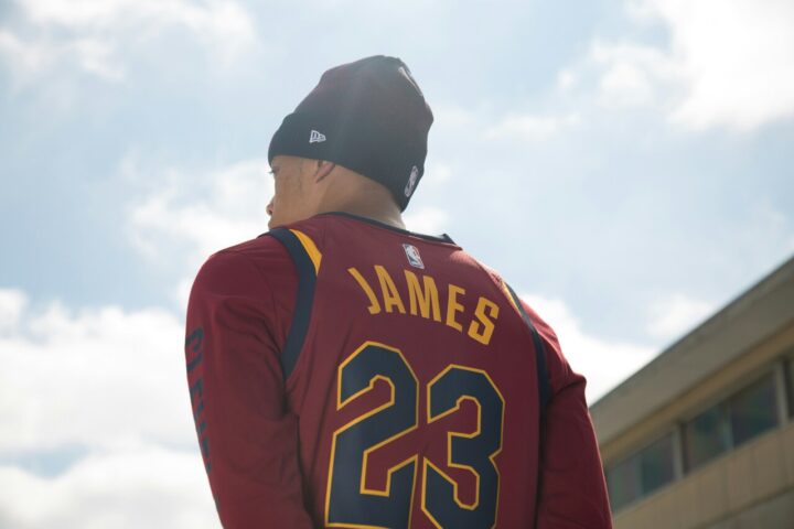 Pessoa de costas vestindo a camisa 23 de LeBron James do Cleveland Cavaliers e touca preta contra o céu azul.